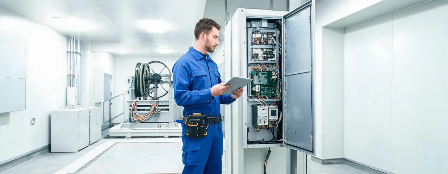 Kone technician servicing elevator controller in machine room